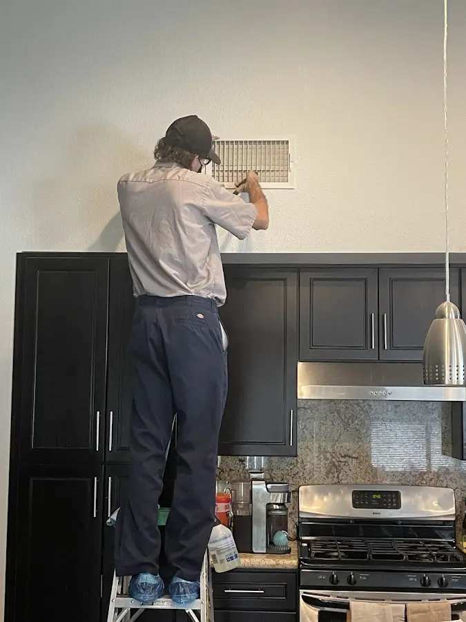 Technician inspecting an air vent during HVAC service in Shaw Heights